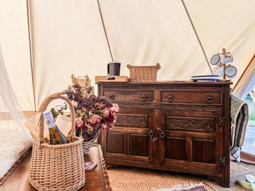 a wooden dresser with a basket of flowers next to it at The Belle Tent in Otterburn