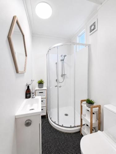 a white bathroom with a shower and a sink at CitiRooms Auckland in Auckland