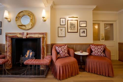 a living room with two chairs and a fireplace at The Capital Hotel, Apartments & Townhouse - Small Luxury Hotels of The World in London