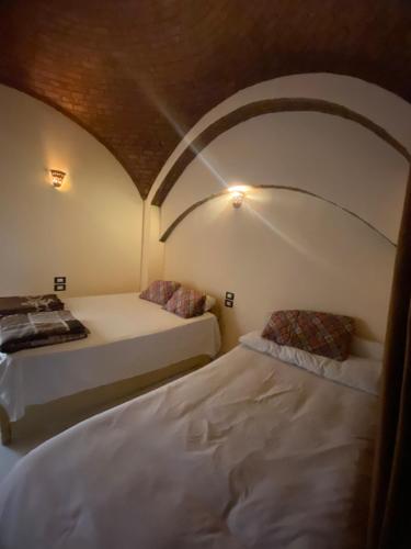 two beds in a room with an arched ceiling at Hooly Nubian in Aswan