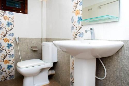 a bathroom with a sink and a toilet and a mirror at Kiula Resort in Hambantota