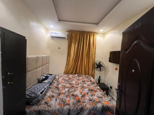 a bedroom with a bed with a comforter on it at Etsuko hotel and suites world city in Atan