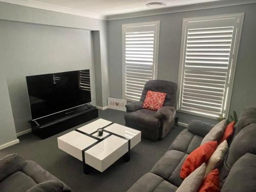 a living room with two couches and a tv at The Snug Suite in Cooranbong