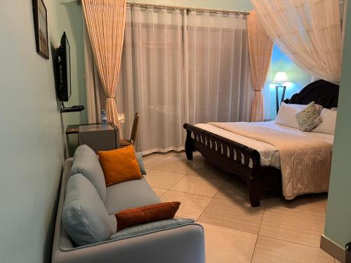 a bedroom with a bed and a couch and a chair at Lakepoint Villa in Entebbe