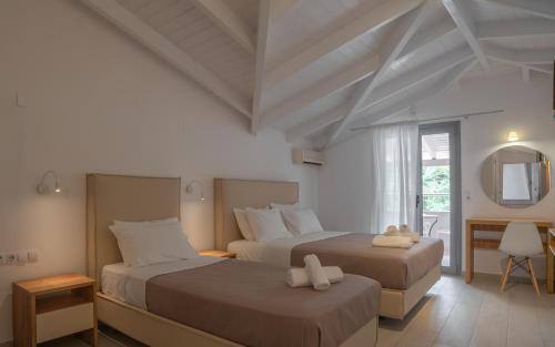 a bedroom with two beds and a mirror at Achilleas Hotel in Parga