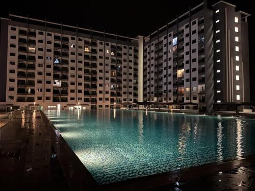a large swimming pool in front of a building at night at Riverfront Homestay at Ambience Residence in Malacca