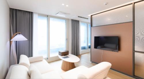 a living room with a white couch and a tv at 플럼바고올스위트402 in Chosan-ni