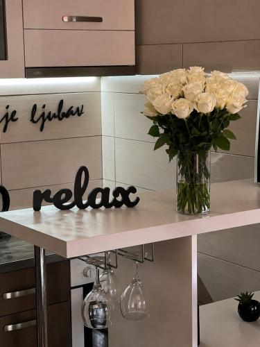 a vase of flowers on a counter with a vase of roses at Mirkovic Lux apartman in Niš