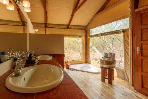 a bathroom with a sink and a large window at Lion Tree Top Lodge in Guernsey Nature Reserve