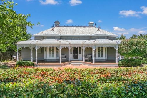a white house with a conservatory in a garden at Central Charm in Echuca