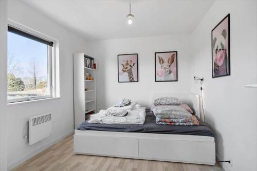 a white bedroom with a bed and a window at 8242-Vordingborg-Kvaedevej-8 in Bakkebølle Fredskov
