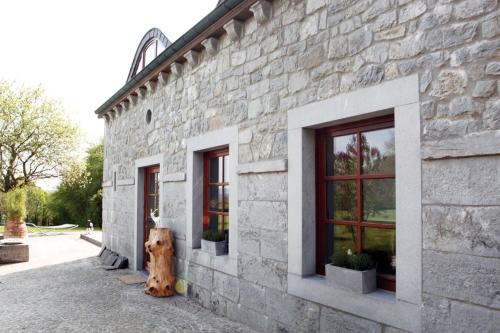 a dog is sitting outside of a stone building at Le Durbuy Lodge in Durbuy