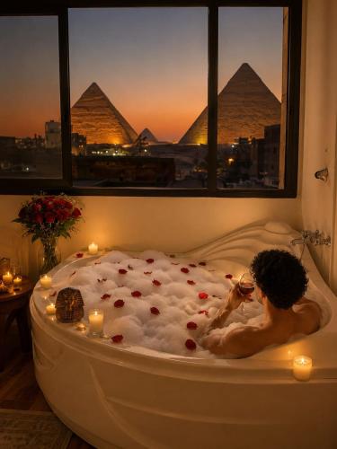 a man sitting in a bath tub in front of the pyramids at panorama pyramids and jacuzzi in Giza