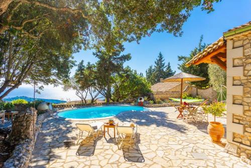 a pool in a yard with chairs and a table at Villa Nionios in Vlachopoulátika