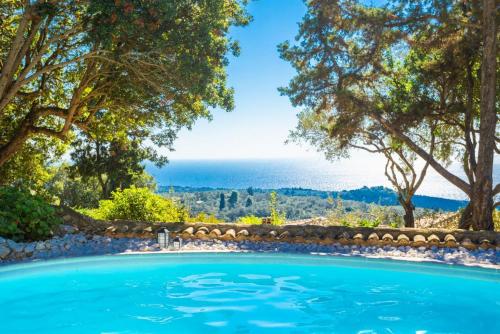 a swimming pool with trees and the ocean in the background at Villa Nionios in Vlachopoulátika