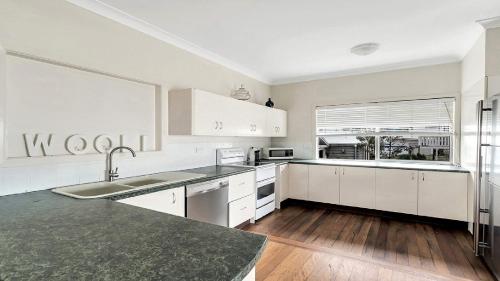 a kitchen with white cabinets and a stainless steel refrigerator at On The Beach in Wooli