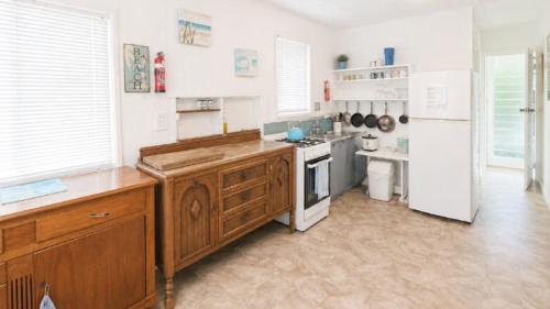 a kitchen with wooden cabinets and a white refrigerator at The Blue Groper in Minnie Water