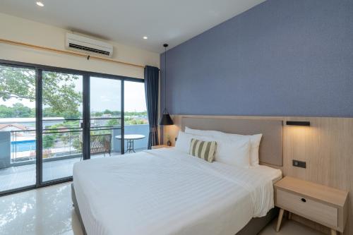 a bedroom with a large white bed and a large window at Aster Canopy Suites & Living in Rayong