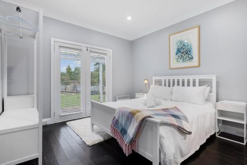 a white bedroom with a bed and a window at Edelweiss Cottage in Berridale