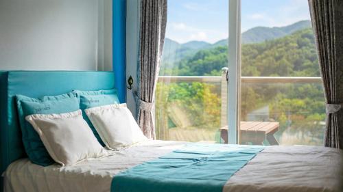a bedroom with a bed and a large window at gapyeong newcastle pension in Gapyeong