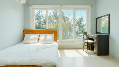 a bedroom with a bed and a desk and a window at Namhae baramundeok Pension in Namhae
