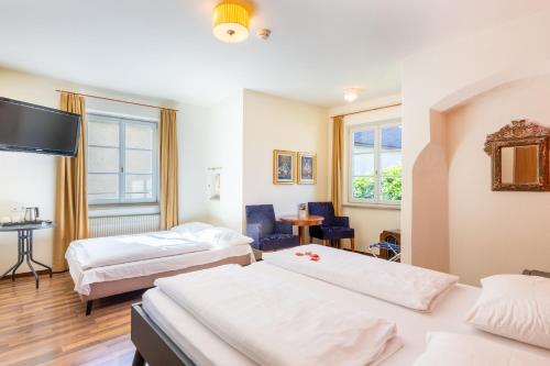 une chambre d'hôtel avec deux lits et une télévision à écran plat dans l'établissement Hotel Traube, à Bressanone