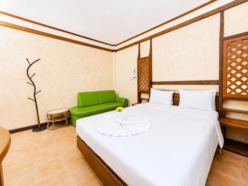 a bedroom with a white bed and a green couch at Chalet De Palm Resort Hatyai in Hat Yai