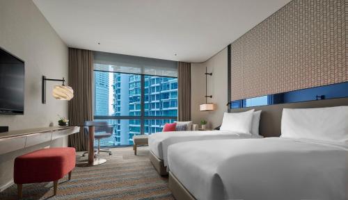 a hotel room with two beds and a television at Amari Kuala Lumpur in Kuala Lumpur