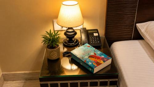 a nightstand with a lamp and a book and a telephone at Smyle Inn - Comfort & Value near New Delhi Railway Station - since 1998 in New Delhi