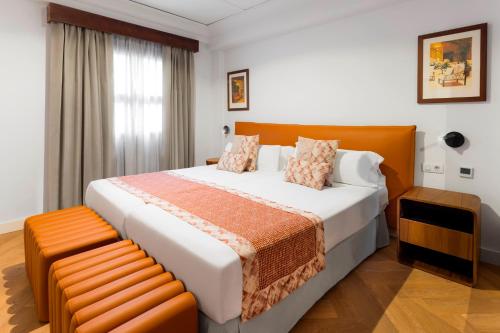 a bedroom with a large bed and a bench at Marylanza Suites & Spa in Playa de las Americas