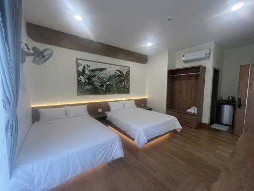 a bedroom with two beds and a painting on the wall at Minh's homestay in Long Bình