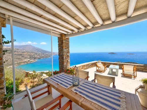 a patio with a table and chairs and the ocean at "GOLDEN SUNSET VILLA" 3-BDR, Breathtaking Views in Batsi