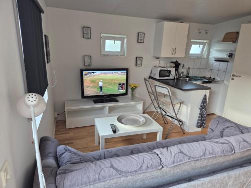 a living room with a couch and a tv and a kitchen at Den fräscha lägenheten in Ängelholm