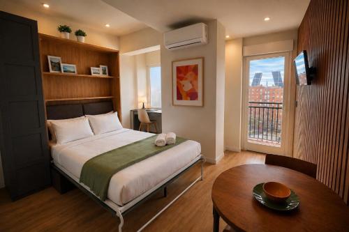 a bedroom with a bed and a table and a window at Winahost Madrid Towers II in Madrid