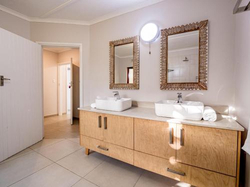 a bathroom with two sinks and two mirrors at Serenity Place B&B and Conference, wedding venue in Durban