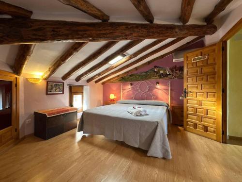 a bedroom with a bed in a room with wooden floors at Entrefrutales · Casa Rural entre Árboles y Aromas in La Vilueña