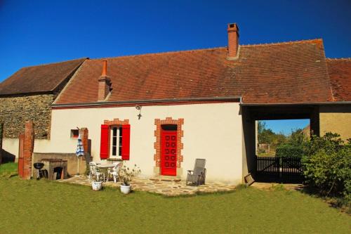 a white house with a red door and a yard at Gite cosy 4 pers en vallée de la Creuse in Baraize
