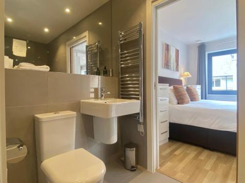 a bathroom with a sink and a toilet and a bed at Your Space Apartments - Eden House in Cambridge