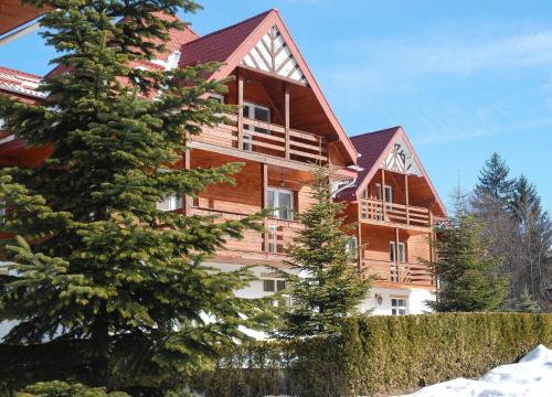 a large wooden house with trees in front of it at Monterai Resort in Poiana Brasov