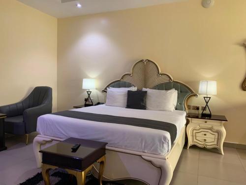 a hotel room with a large bed and a chair at Corporate Residence in Port Harcourt