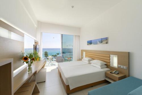 a bedroom with a bed and a view of the ocean at Vrissaki Beach Hotel in Protaras