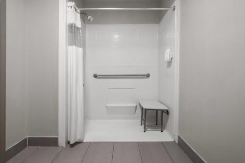 a white bathroom with a shower and a table at Days Inn by Wyndham Norfolk Airport in Norfolk