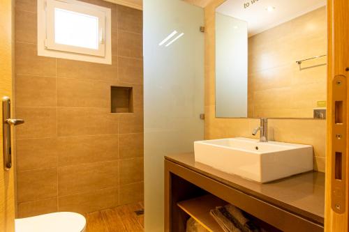 a bathroom with a white sink and a mirror at Eriphilly Studios & Apartments in Mythimna