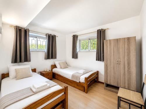 two beds in a room with two windows at Le logis de Louze in Saint-Maurice-lʼExil
