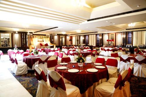 um salão de banquetes com mesas e cadeiras vermelhas e brancas em Regent Park Hotel em Jalandhar