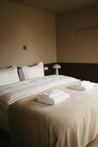 a bedroom with a large white bed with towels on it at Aurora Farm Hotel in Laugar