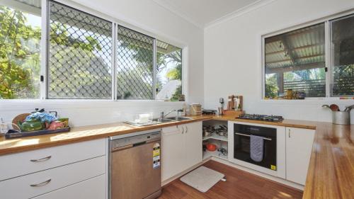 a kitchen with white cabinets and windows at Pinchin's Place in Brunswick Heads