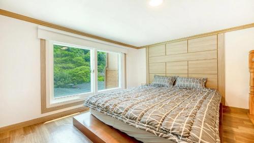 a bedroom with a large bed and a window at Gapyeong Swimteo Pet Pension in Gapyeong