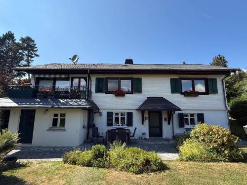 a white house with a balcony on top of it at Haus am Rotkreuzweg mit Pool in Feldberg