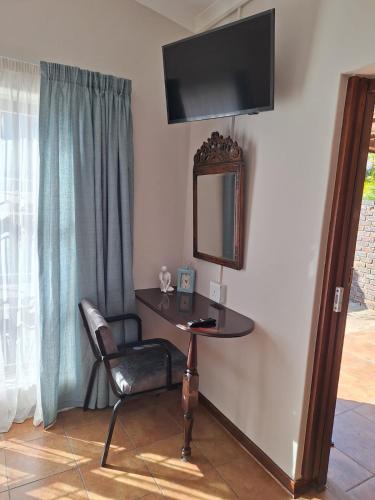 a desk with a chair and a mirror on a wall at Cozy Room in Ellisras